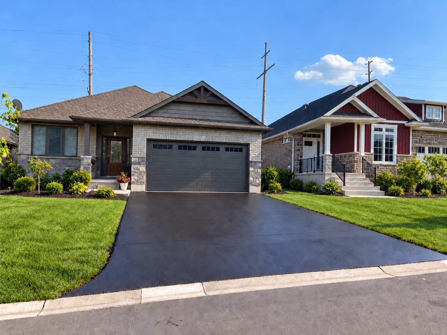 Glossy black asphalt driveway leading to a charcoal two-car garage door on a single-story brick and stone house